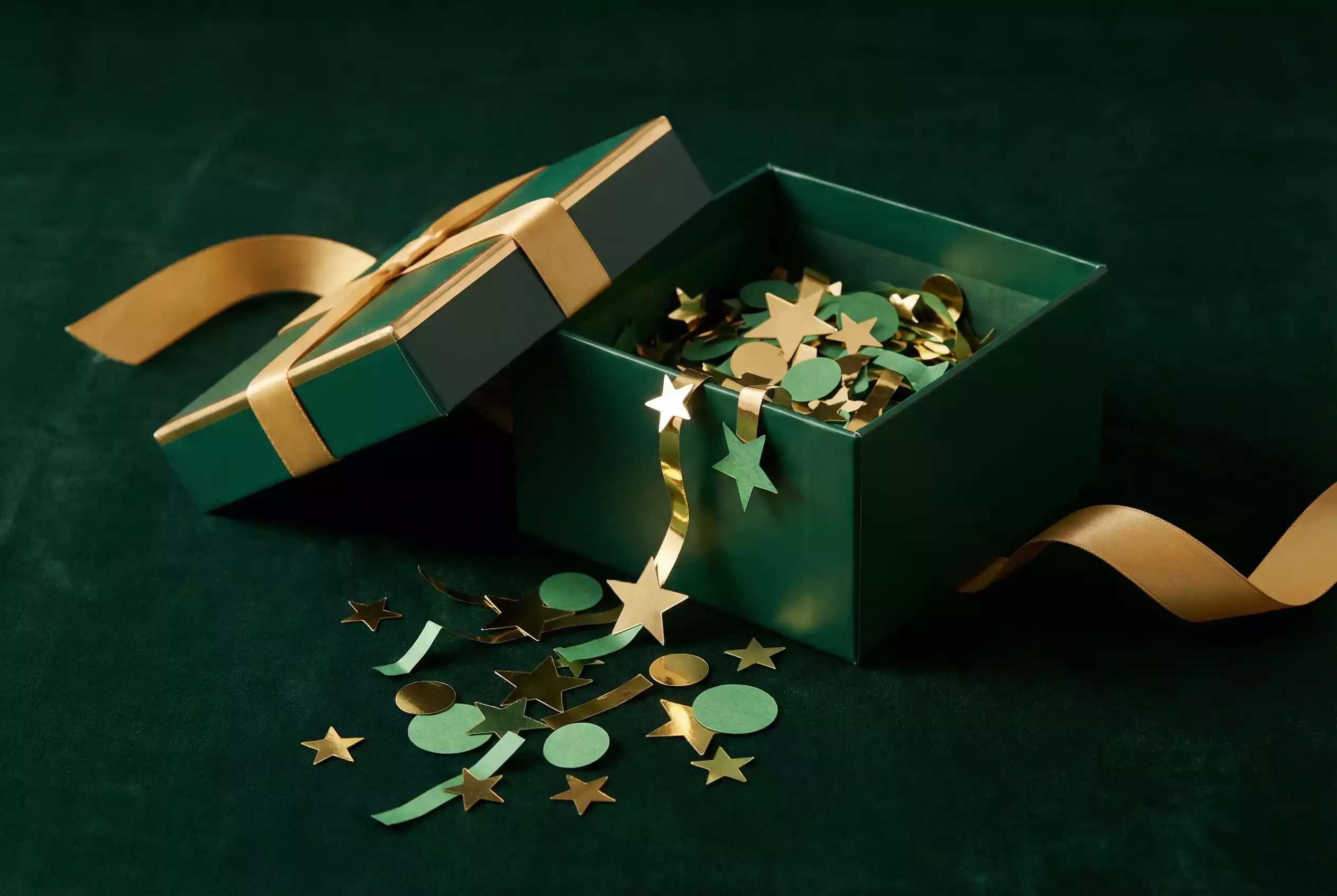 Caixa de presente aberta com confetti sobre fundo verde escuro