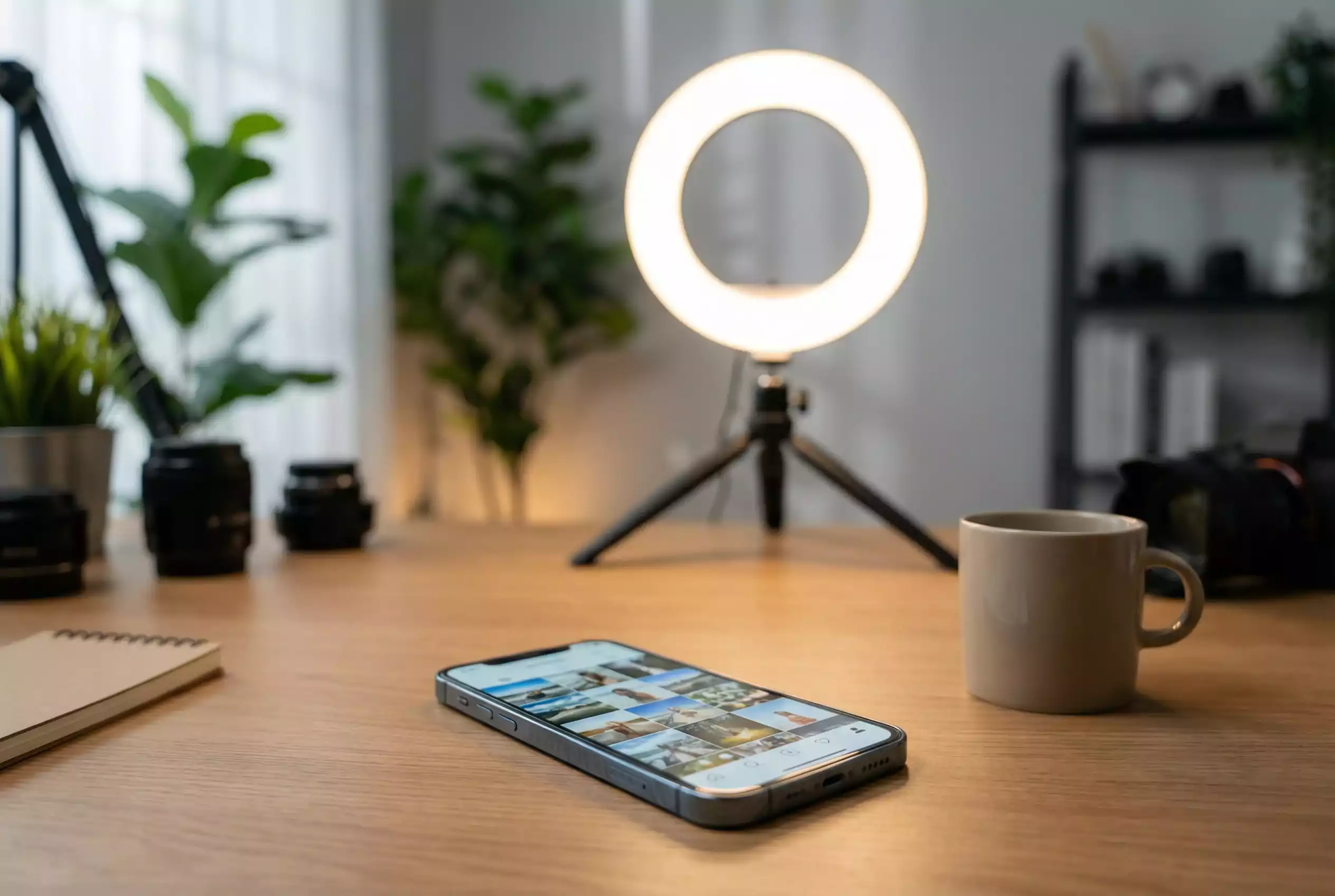 Smartphone com aplicação de rede social aberta sobre uma mesa com ring light ao fundo